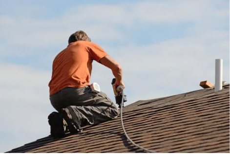 man on top of roof making roof repairs